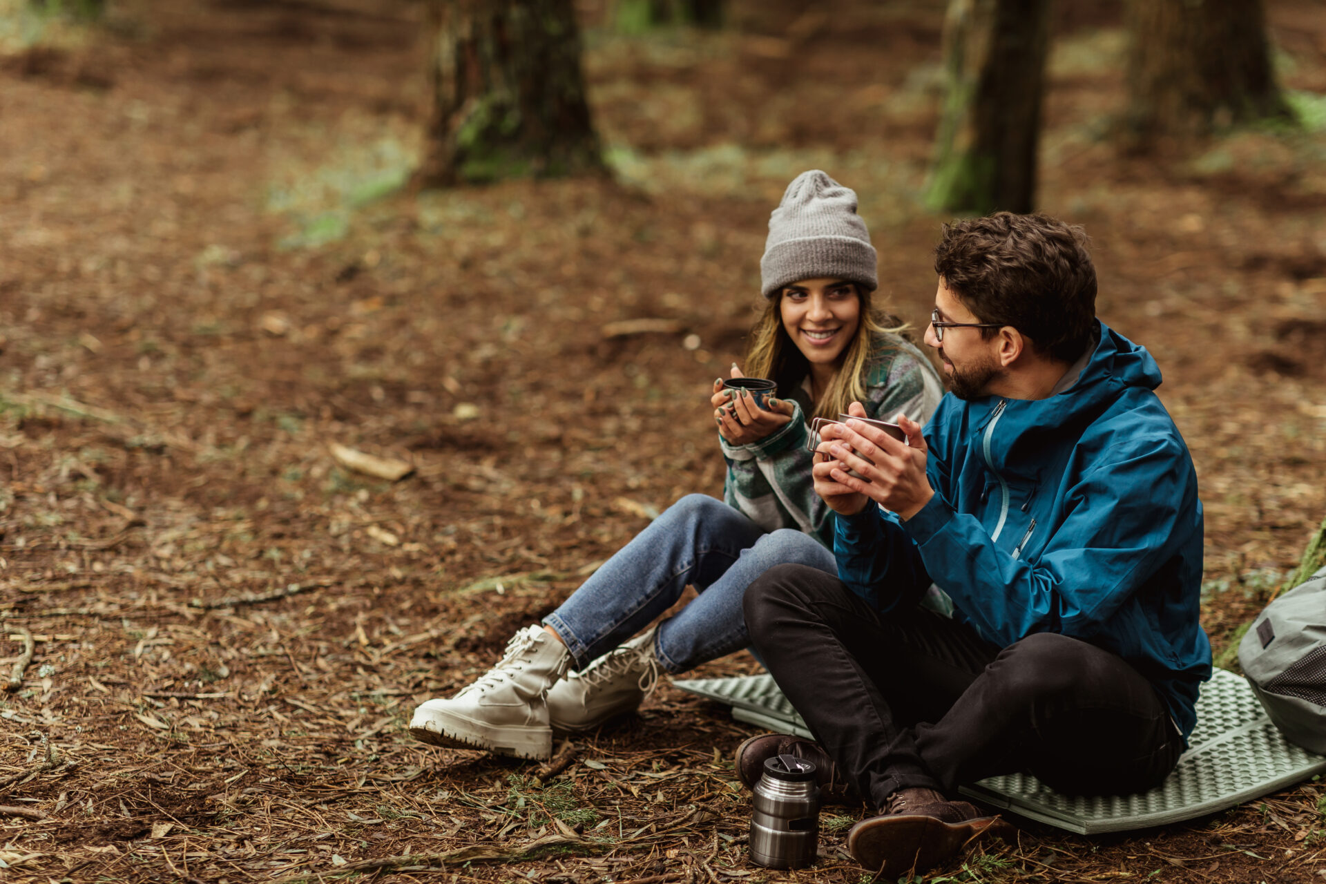 Accueil - Cheerful young caucasian couple in jackets in forest drinking cups of tea from thermos, enjoy travel, vacation - Outdoor Starterkit