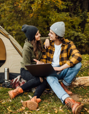 Accueil - Loving couple of young freelancers watch film in the forest near tent. - Outdoor Starterkit
