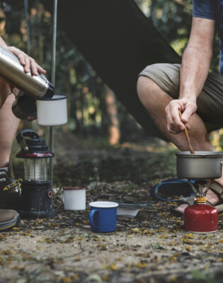 Accueil - Mature man cooking at a campsite - Outdoor Starterkit
